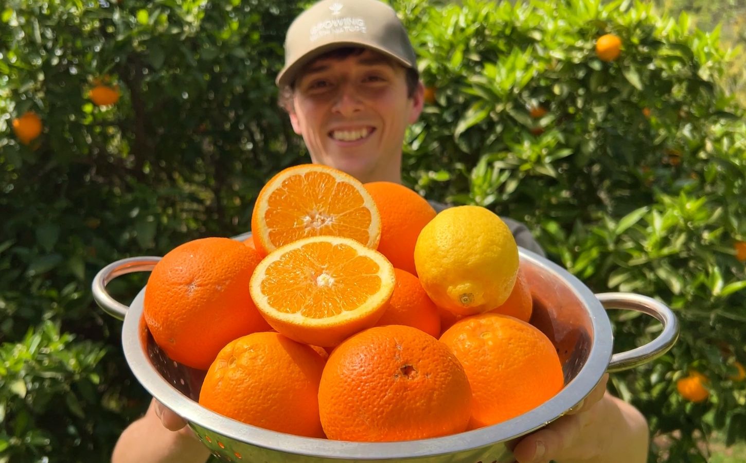 Vegan homesteader Luke Kelsall holding up a tub of oranges that he grew himself