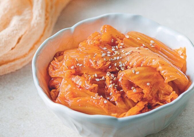 a bowl of vegan kimchi with cabbage, garlic, mushrooms, and Korean chili powder