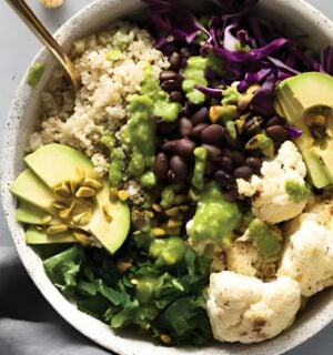 a warming cauliflower and quinoa bowl with avocado, black beans, basil pesto, and cauliflower