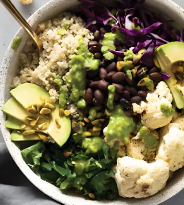 a warming cauliflower and quinoa bowl with avocado, black beans, basil pesto, and cauliflower