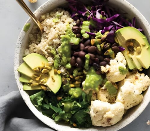 a warming cauliflower and quinoa bowl with avocado, black beans, basil pesto, and cauliflower