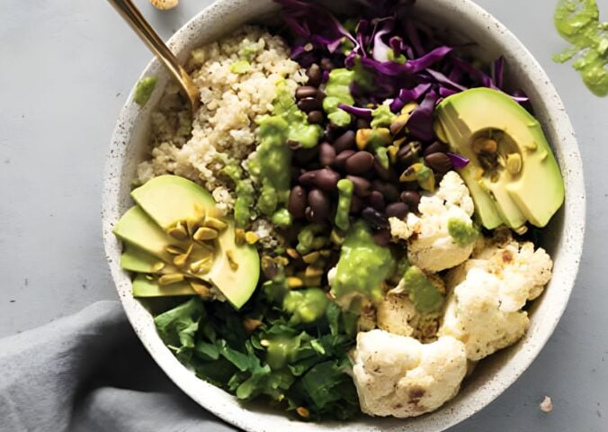 a warming cauliflower and quinoa bowl with avocado, black beans, basil pesto, and cauliflower