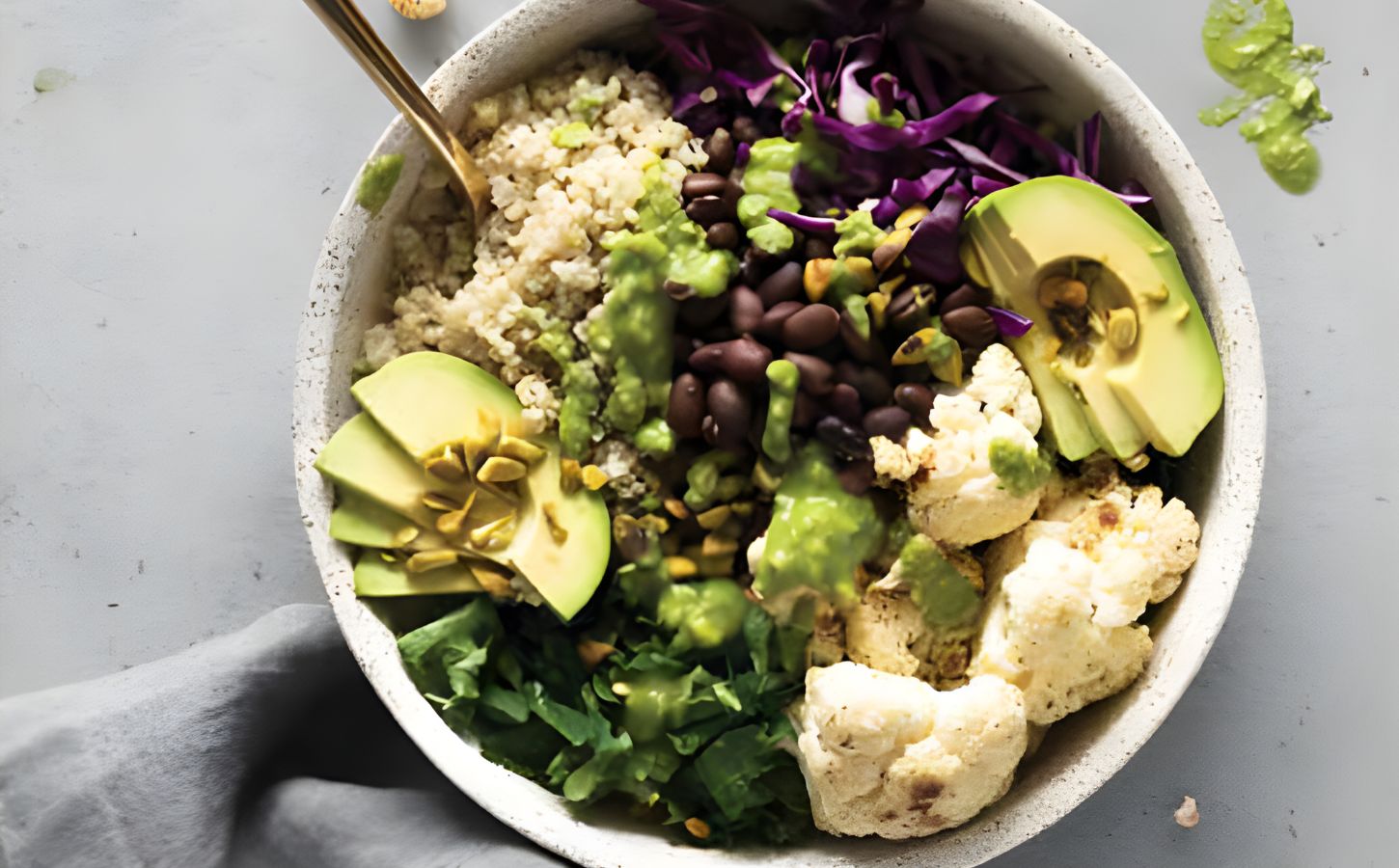 a warming cauliflower and quinoa bowl with avocado, black beans, basil pesto, and cauliflower