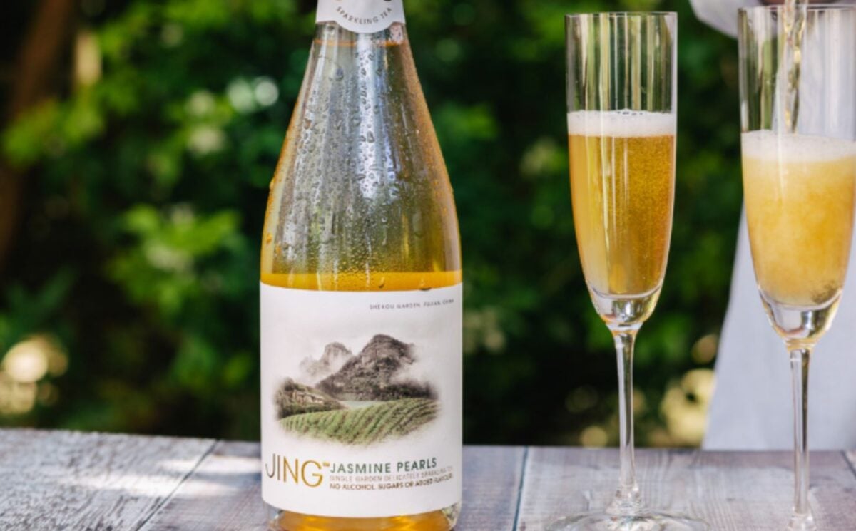 Photo shows a bottle of JING sparkling tea alongside two champagne-style glasses