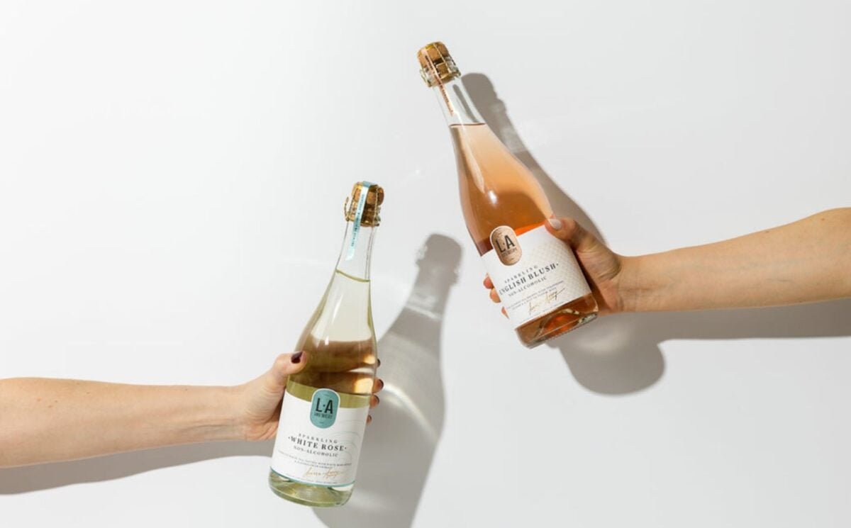 Photo shows to people's hands as they "cheers" two bottles of LA Brewery's sparkling tea