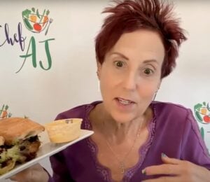 Chef AJ holding up a vegan sandwich, which she describes