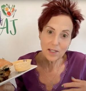 Chef AJ holding up a vegan sandwich, which she describes