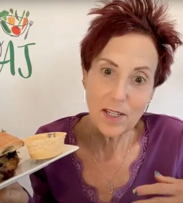 Chef AJ holding up a vegan sandwich, which she describes