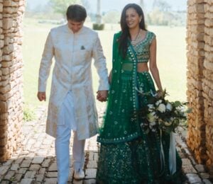 Photo shows Klaus and Kamal walking through a cobbled archway in their wedding outfits