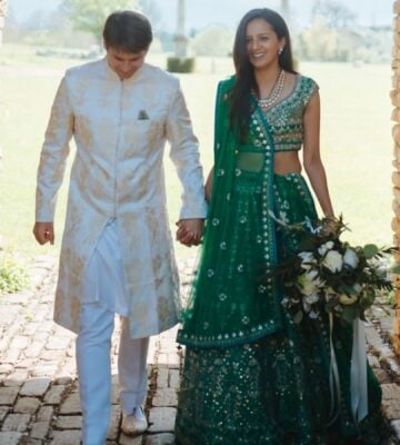 Photo shows Klaus and Kamal walking through a cobbled archway in their wedding outfits