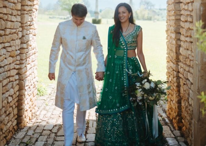 Photo shows Klaus and Kamal walking through a cobbled archway in their wedding outfits