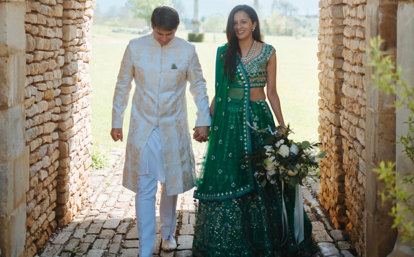 Photo shows Klaus and Kamal walking through a cobbled archway in their wedding outfits