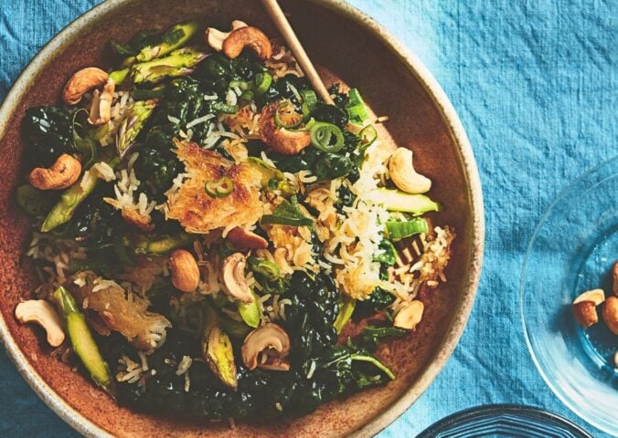 a bowl of crispy rice salad with crunchy vegetables and a side of cashew nuts