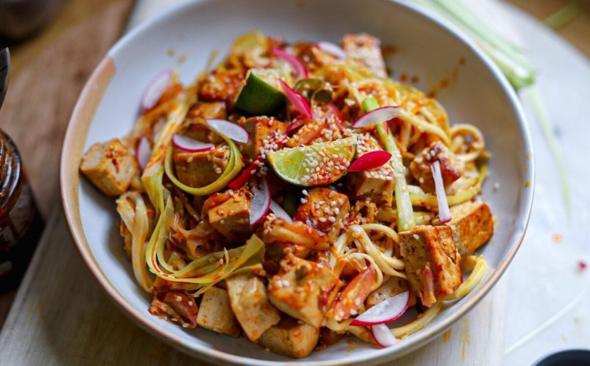 a bowl of crispy tofu stir fry with leek and chili topped with lime