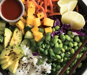 a deconstructed sushi bowl with edamame, avocado, carrot, and mango
