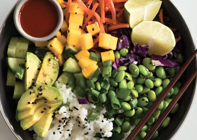 a deconstructed sushi bowl with edamame, avocado, carrot, and mango