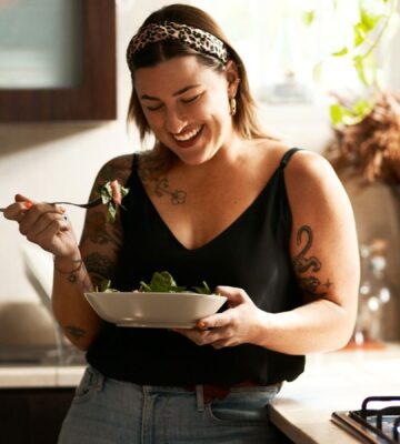 A woman eating a bowl of longevity superfood beans in a kitchen