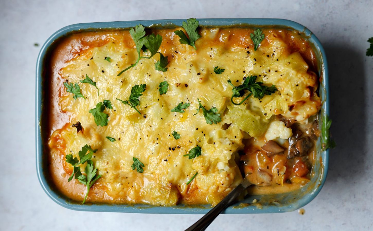 meat-free cottage pie with leek and cauliflower topping plus mushrooms, vegan grated cheese, and herbs