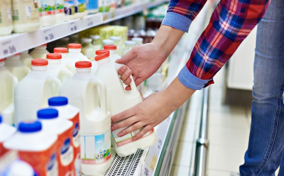 A man picking up a carton of milk from a supermarket