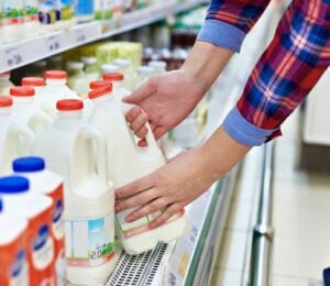 A man picking up a carton of milk from a supermarket