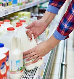 A man picking up a carton of milk from a supermarket