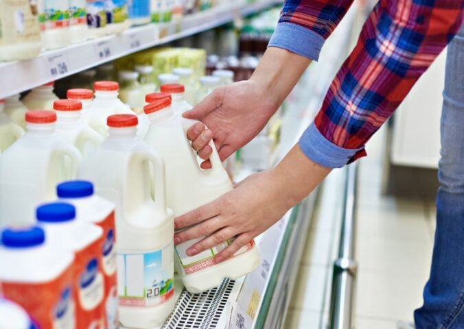 A man picking up a carton of milk from a supermarket