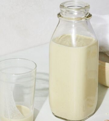 a picture of a bottle of perfect pistachio milk with s glass, cheesecloth, and whole pistachio nuts