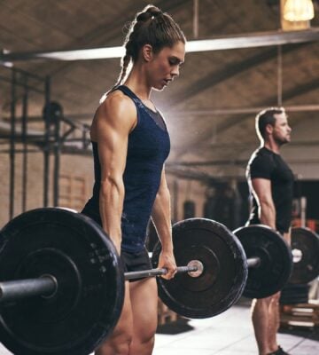 A woman and man lifting heavy weights at the gym