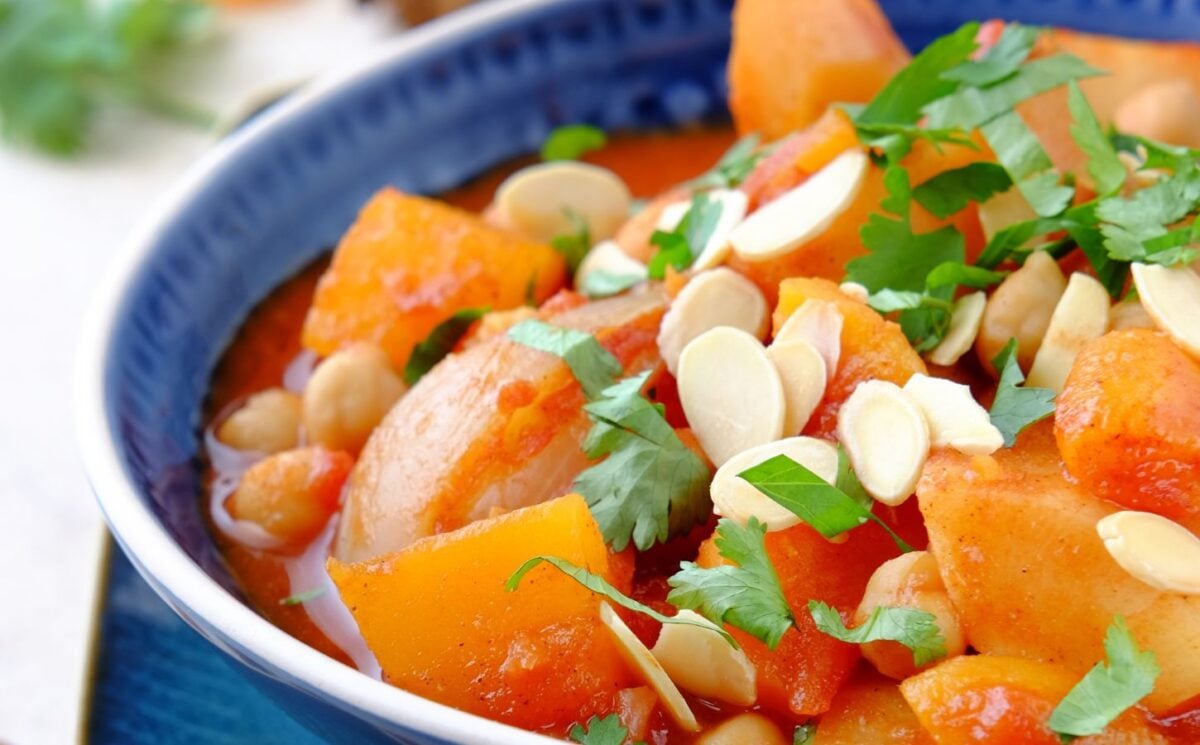 a picture of a seasonal root vegetable tagine topped with almonds and coriander, part of recipes containing five vegetables or more