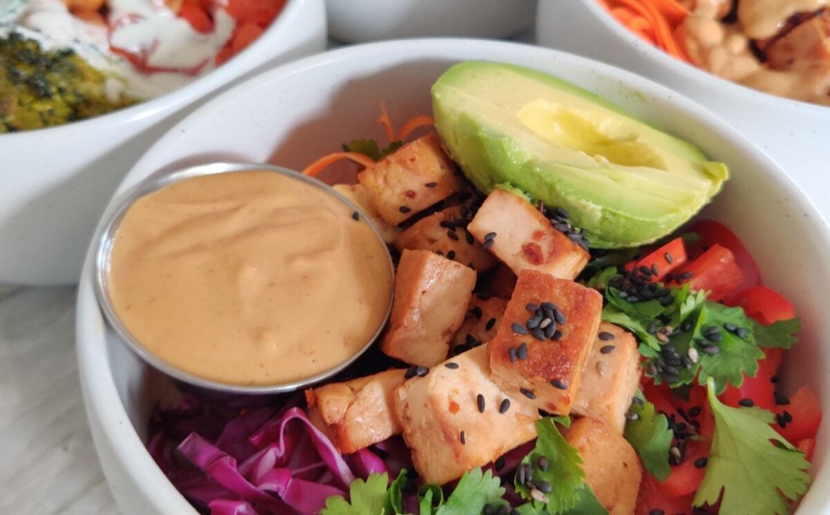 a picture of a vegan rice power bowl with peanut sauce, avocado, tofu, cucumber, bell pepper, brown rice perfect for vegan power bowl recipes