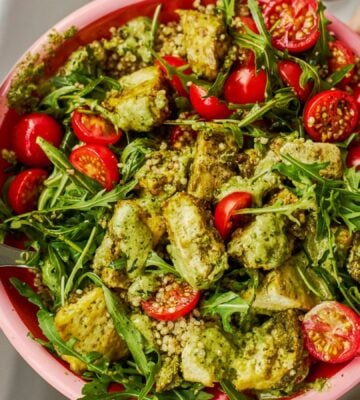 a baked pesto tofu bro bowl with tofu, quinoa, cherry tomatoes and rocket as part of vegan power bowl recipes