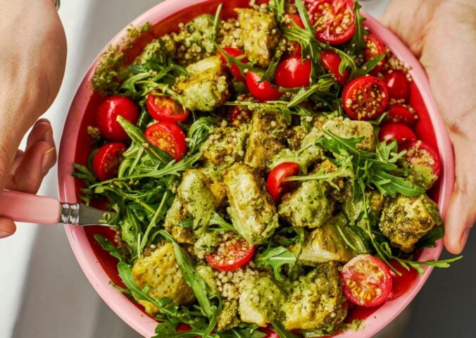 a baked pesto tofu bro bowl with tofu, quinoa, cherry tomatoes and rocket as part of vegan power bowl recipes