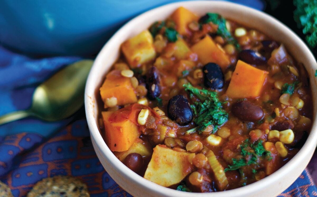 a bowl of sweet potato and kale chili with avocado, corn, kidney beans, and lentils, part of recipes containing five vegetables or more