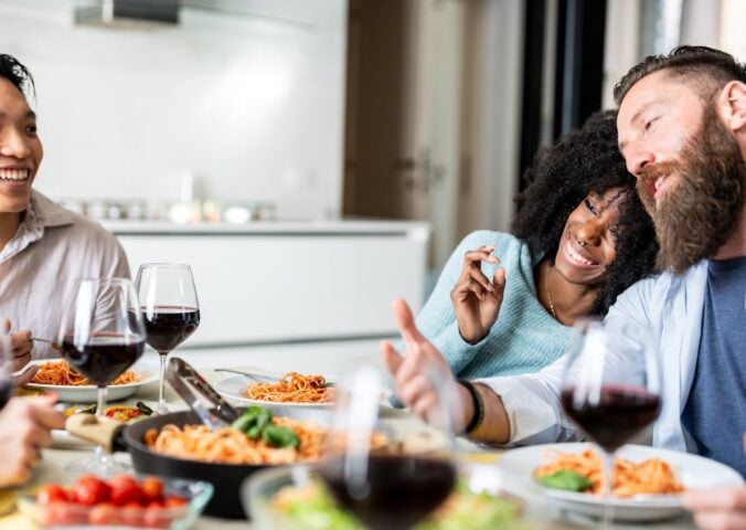 Friends sitting down to eat spaghetti after taking part in Veganuary