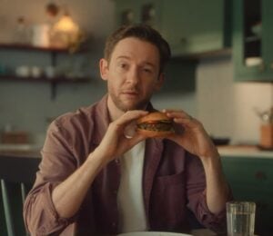 Screengrab from the new Beyond Meat advertisement shows someone eating a plant-based burger in a kitchen