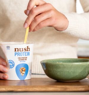 A person spooning a Nush high protein, soy-free yogurt