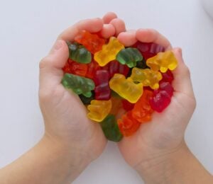 Photo shows a child's hands as he cups jelly beans in the shape of a heart