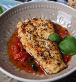 Photo shows two fillets of the latest Revo Foods product, vegan black cod, in a dish with a tomato-based sauce and green garnish