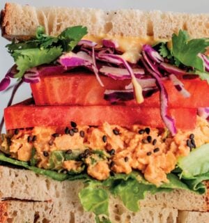 a picture of stacked peanut miso chickpea salad sandwiches with sesame, tomato, chickpea spread, and greens as part of vegan spring lunch ideas