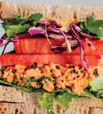 a picture of stacked peanut miso chickpea salad sandwiches with sesame, tomato, chickpea spread, and greens as part of vegan spring lunch ideas