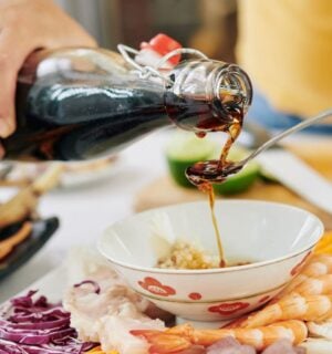 Photo shows someone pouring soy sauce from a glass bottle into a spoon