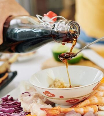 Photo shows someone pouring soy sauce from a glass bottle into a spoon