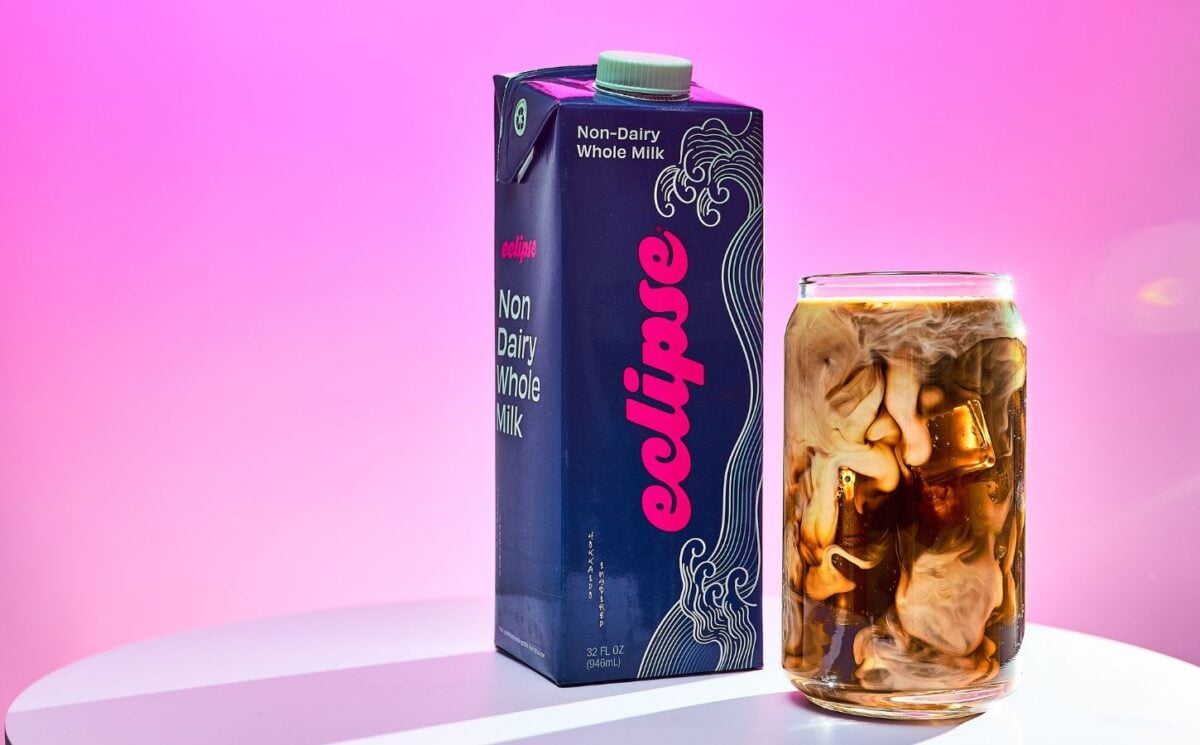 Photo shows a carton of the new plant-based whole milk from Eclipse Foods next to an iced coffee, set against a pink background