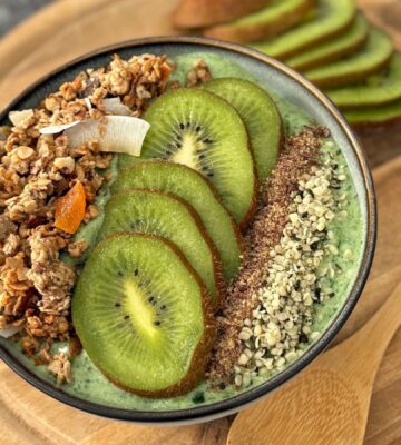 A green smoothie bowl with fruit and granola toppings, a healthy plant-based breakfast