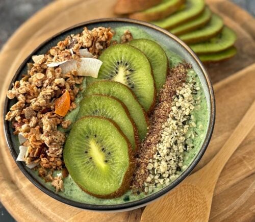 A green smoothie bowl with fruit and granola toppings, a healthy plant-based breakfast