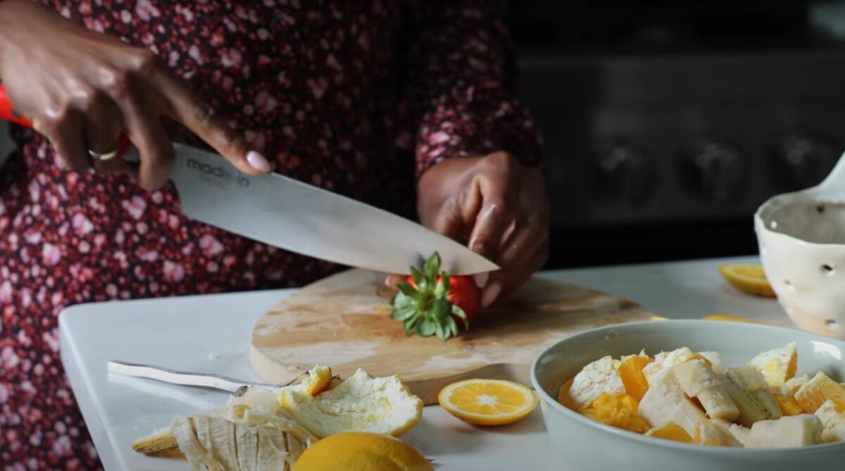 Jenné Claiborne from SweetPotatoSoul cutting up fruit for a fruit salad