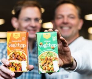 Photo shows Oh So Wholesome founders Jason Gibb and Simon Day holding up packets of their flagship “Veg’chop" product