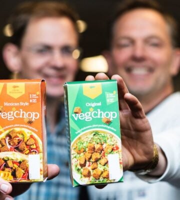 Photo shows Oh So Wholesome founders Jason Gibb and Simon Day holding up packets of their flagship “Veg’chop" product