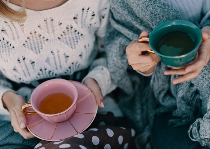 Photo shows two women drinking cups of herbal tea