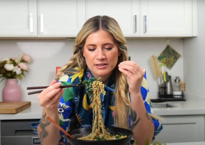 Candice Hutchings eats a bowl of ramen in a video featuring realistic high protein meals that she eats in a day